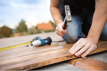 man with hammer on plank of wood